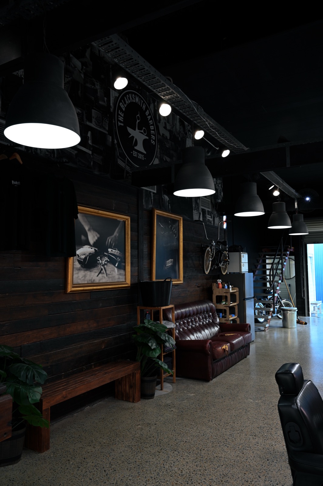 The Blacksmith barbershop floor — industrial lights, leather lounge and the Est. 2015 wall