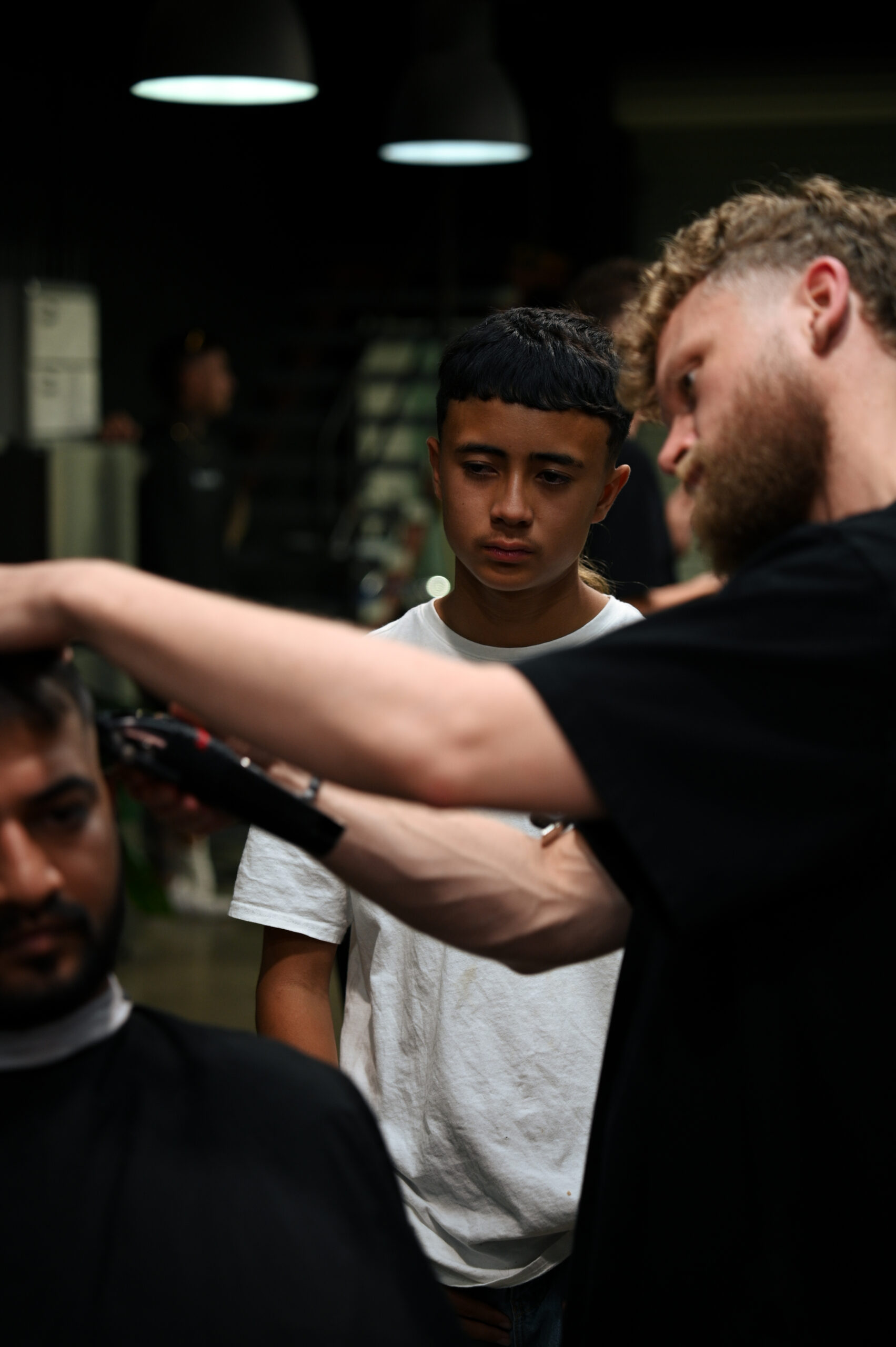 A senior Blacksmith barber mentoring a student on the floor