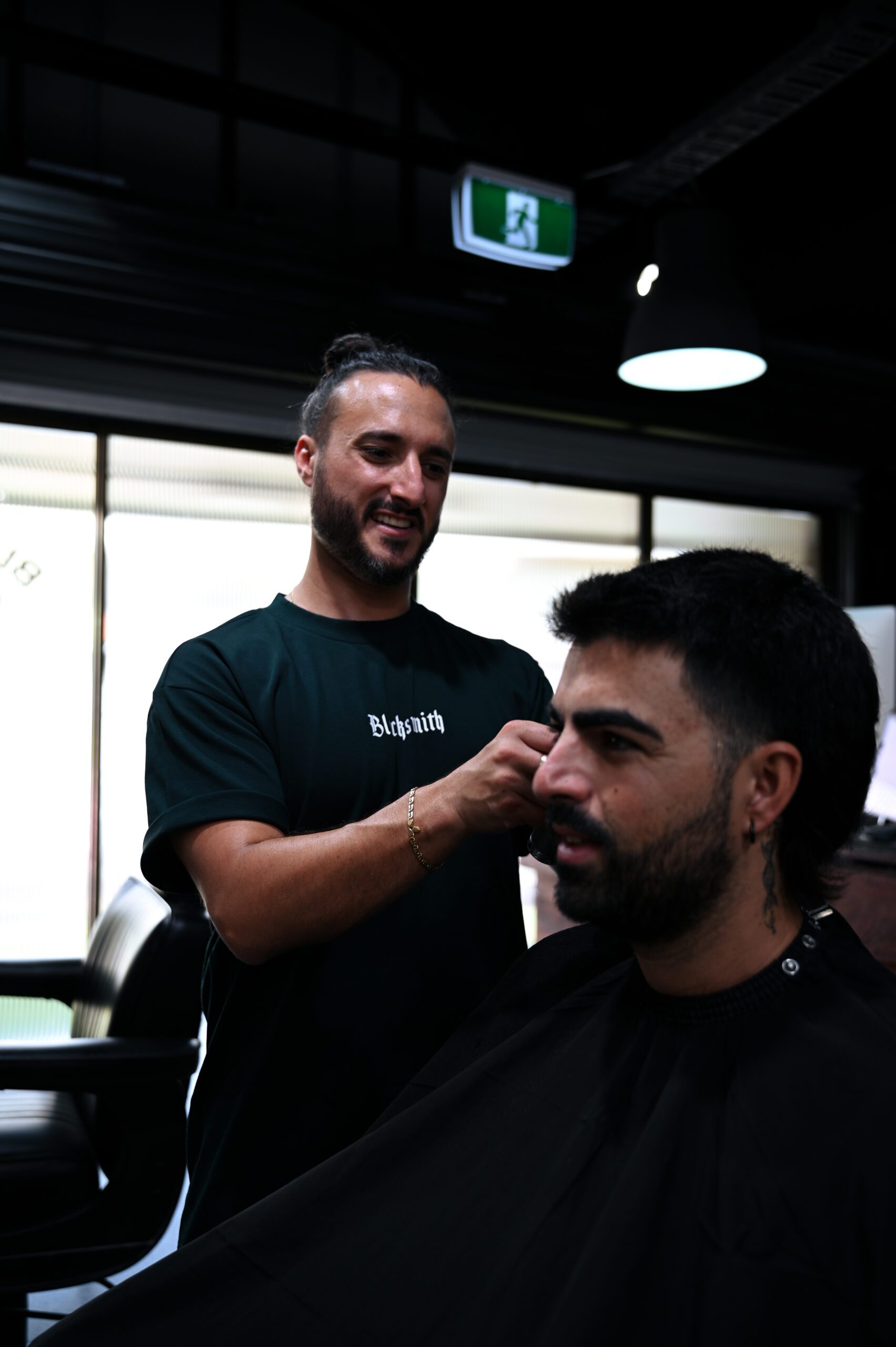 A Blacksmith barber sharing a laugh with a client mid-cut